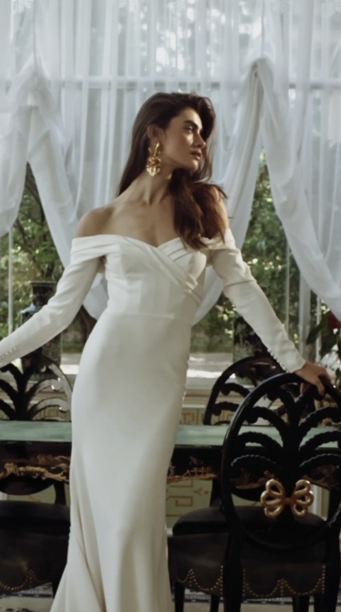 Photo of the model posing and wearing a white bridal gown